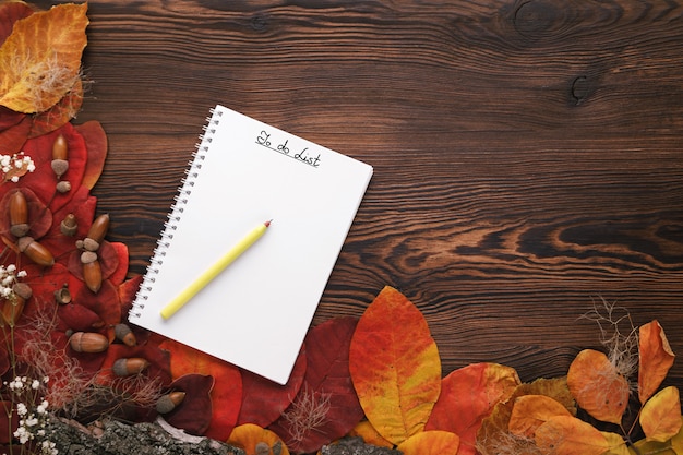 Hojas de otoño, galletas y cuaderno de papel sobre madera