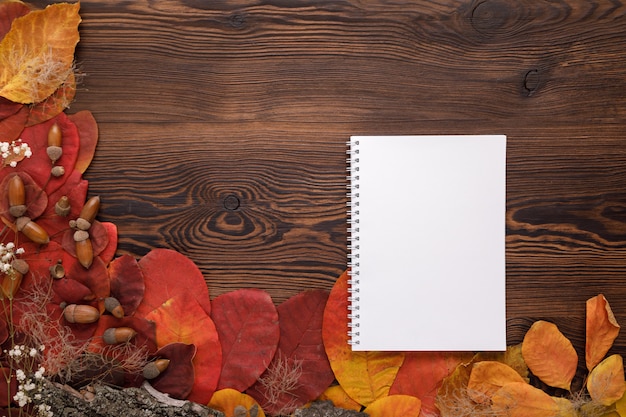 Hojas de otoño, galletas y cuaderno de papel sobre madera