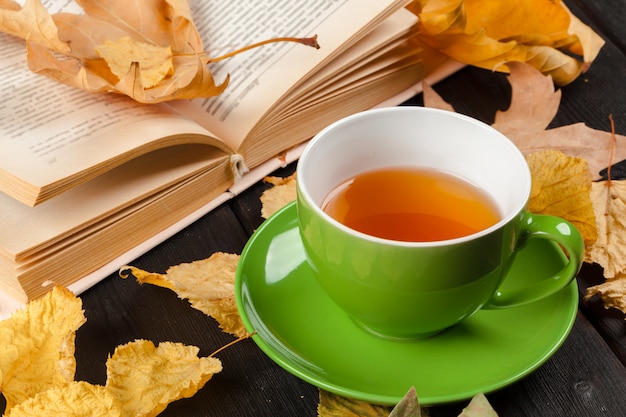 Hojas de otoño, libro y taza de té.