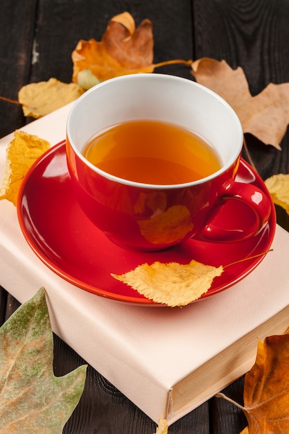 Hojas de otoño, libro y taza de té.