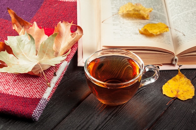 Hojas de otoño, libro y taza de té.