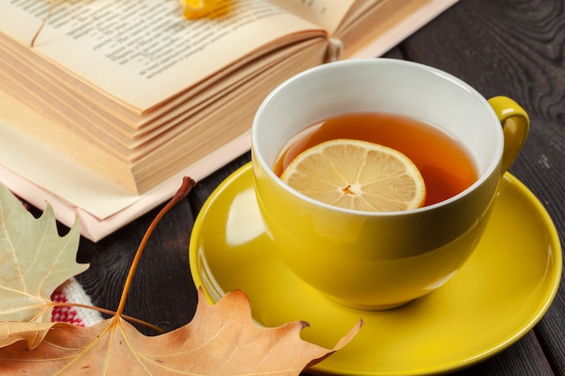 Hojas de otoño, libro y taza de té.