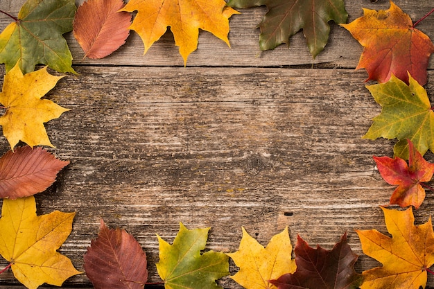 Hojas de otoño sobre superficie de madera con espacio de copia
