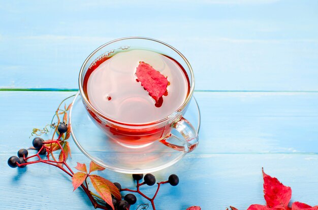 Hojas de otoño y taza de té en la mesa de madera