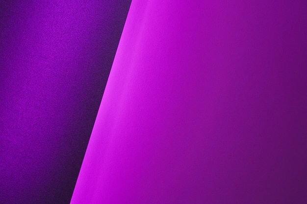Hojas de papel en blanco enrolladas en una iluminación de neón púrpura de cerca