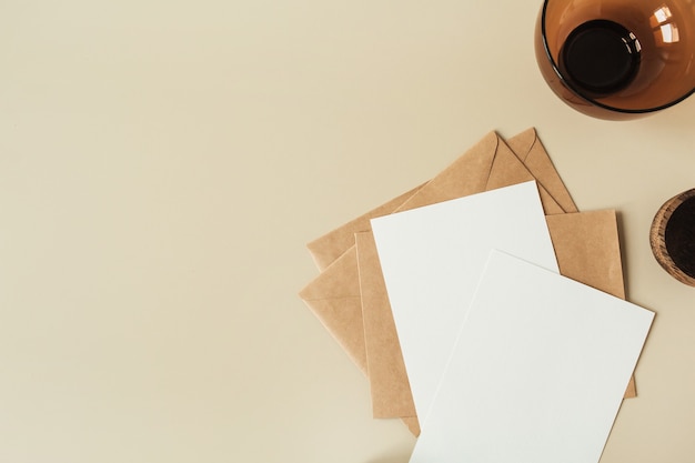 Hojas de papel en blanco con espacio de copia vacío para texto, sobres en superficie beige