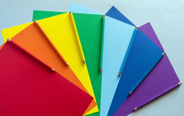 Hojas de papel multicolor con lápices de colores. Colores del arcoiris. Símbolo de la comunidad LGBT