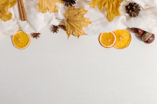 Hojas secas, especias, bufanda y naranjas sobre la mesa. Humor de otoño, copyspace, luz de la mañana.