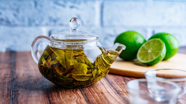 Las hojas de té se preparan en agua hirviendo y se infunden en una tetera pequeña El concepto de la fiesta del té Té verde en una tetera