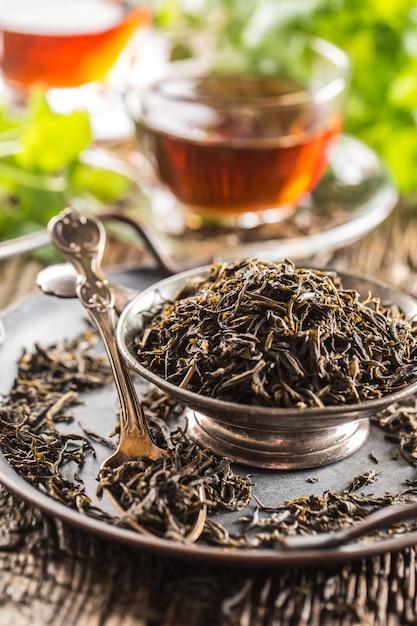 Hojas de té secas en un recipiente sobre la mesa de madera rústica.