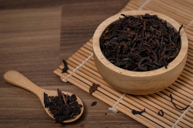 Hojas de té secas en una taza de madera sobre la mesa Té chino de buena calidad con buen olor