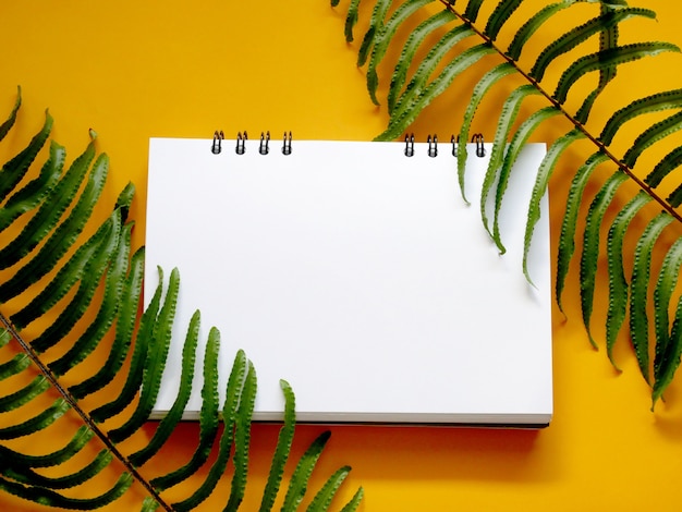 hojas tropicales con cuaderno en blanco