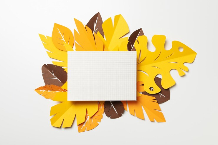 Hojas tropicales de papel amarillo y marrón sobre un fondo claro