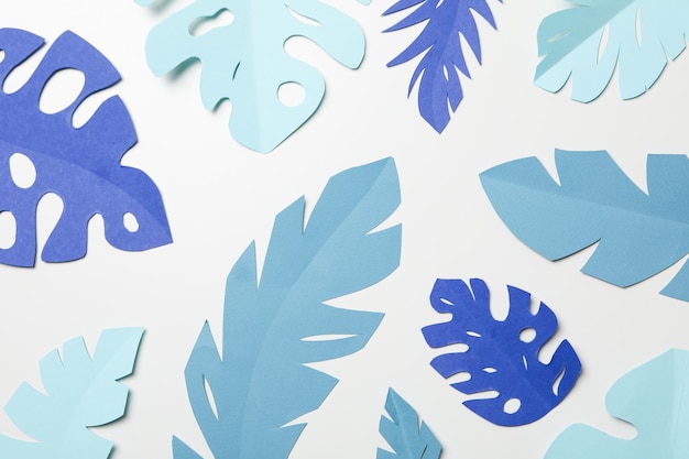 Hojas tropicales de papel azul sobre un fondo claro