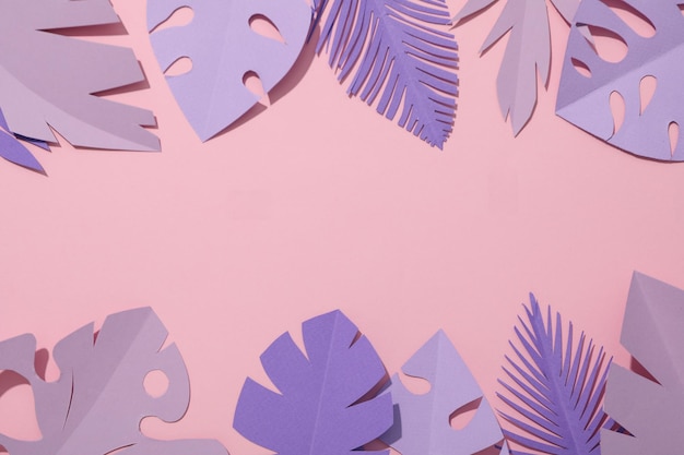 Hojas tropicales de papel púrpura sobre un fondo rosa