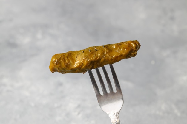 hojas de uva rellenas en un tenedor sobre un fondo blanco coles rellenas