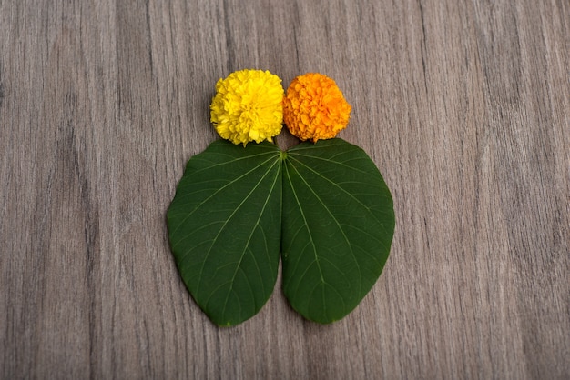 Hojas verdes y flores de caléndula sobre un fondo de madera