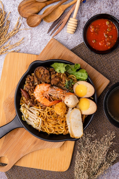 Los Hokkien mee se mezclan con manteca de cerdo y se sirven con bolas de pescado y camarones.