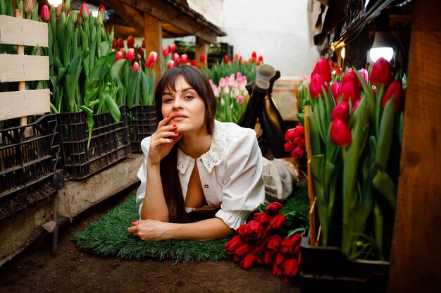 Holanda 23 de março de 2023 Um jardineiro em uma estufa doméstica com tulipas Botas pretas Grama verde Garota sexy