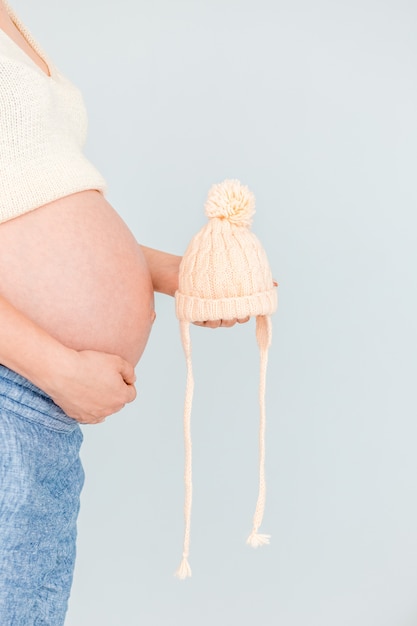 Foto holding der schwangeren frau gestrickt nahe ihrem bauch, der auf die geburt des kindes wartet