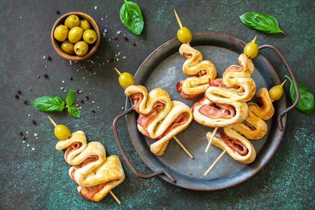 Holiday Snack Blätterteig Weihnachtsbaum mit Oliven und Speck auf einer Schiefer- oder Steintischplatte Weihnachten