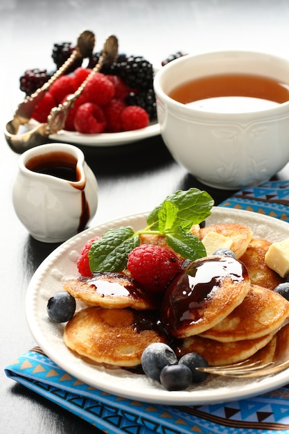 Holländische Minipfannkuchen genannt poffertjes mit Beeren und Schokoladensoße