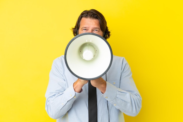 Holländischer Telemarketer, der mit einem Headset arbeitet, das auf gelbem Hintergrund isoliert ist und durch ein Megaphon schreit