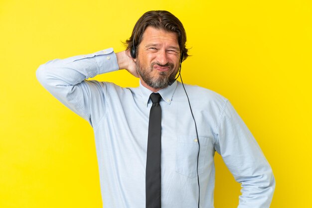Holländischer Telemarketer, der mit einem Headset arbeitet, das auf gelbem Hintergrund mit Nackenschmerzen isoliert ist