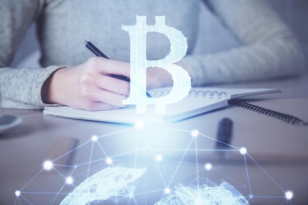 Holograma de criptomoneda sobre las manos de la mujer escribiendo fondo Concepto de blockchain Exposición múltiple