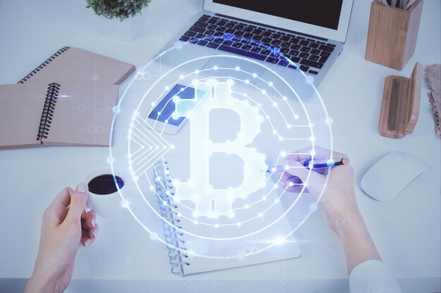 Holograma de criptomoneda sobre las manos de la mujer escribiendo fondo Concepto de blockchain Exposición múltiple