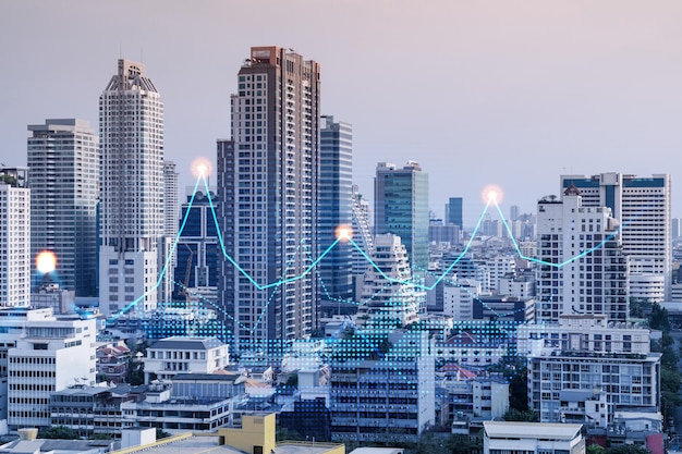 Holograma de gráfico de acciones financieras sobre la vista panorámica de la ciudad del centro de negocios de Bangkok en Asia El concepto de transacciones internacionales Doble exposición