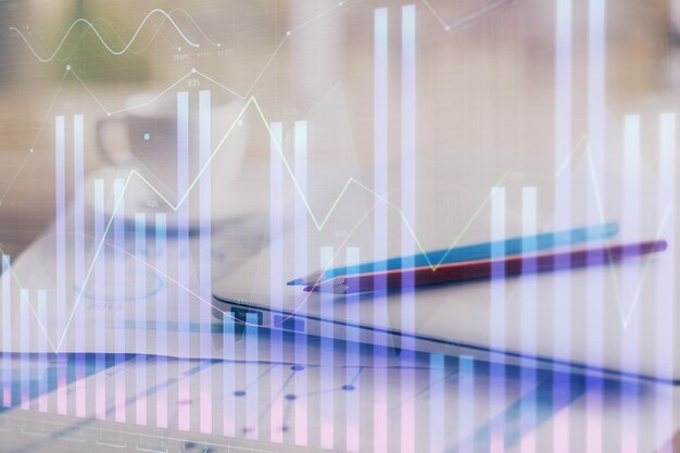 Holograma de gráfico de divisas en la mesa con fondo de computadora Doble exposición Concepto de mercados financieros