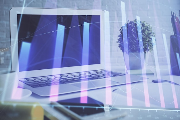 Holograma de gráfico de divisas en la mesa con fondo informático Múltiple exposición Concepto de mercados financieros