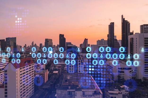 Hologramm von Social-Media-Symbolen über Sonnenuntergang Panorama-Stadtbild von Bangkok Südostasien Das Konzept der Verbindungen zwischen Menschen und Karrieremöglichkeiten Mehrfachbelichtung