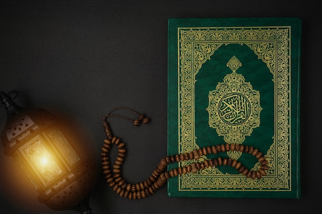 Holy Al Quran con el significado de la caligrafía árabe escrita de Al Quran y rosarios en negro