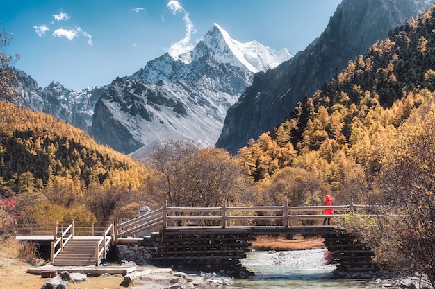 Holy Chana Dorje montaña en otoño bosque de pinos con puente de madera en Shangri-La, Yading