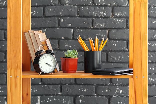Holz Bücherregal mit Büchern und Sachen gegen schwarze Backsteinmauer