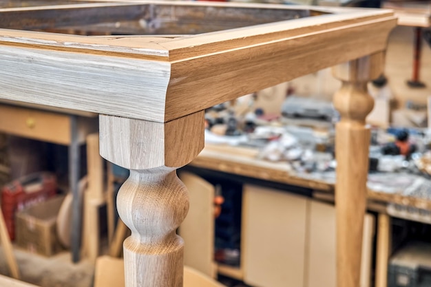 Holz-Esstisch mit geschnitztem Bein aus massiver Eiche und Metallrahmen in Werkstatt-Nahaufnahme
