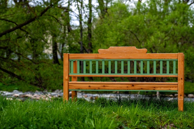 Holzbank in einem grünen Park durch die Rückansicht des Flusses