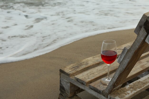 Holzbank mit Glas Wein am Sandstrand