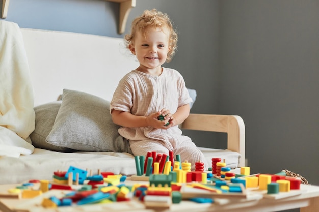 Holzbaukasten Montessori-Lernansatz Rätsel zur kognitiven Entwicklung Glücklich lächelndes kleines blondes Mädchen, das zu Hause mit Sortierspielzeug aus Holz spielt