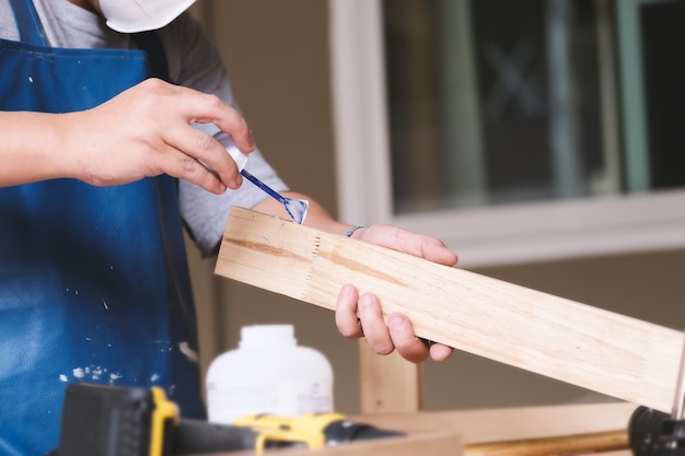 Holzbearbeiter verwenden klebstoff, um die holzteile zusammenzusetzen und einen holztisch für ihre kunden zu montieren und zu bauen