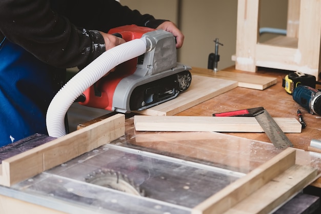 Holzbearbeiter verwenden Sandpapierveredelungsmaschinen, um Holztische für ihre Kunden zu montieren und zu bauen