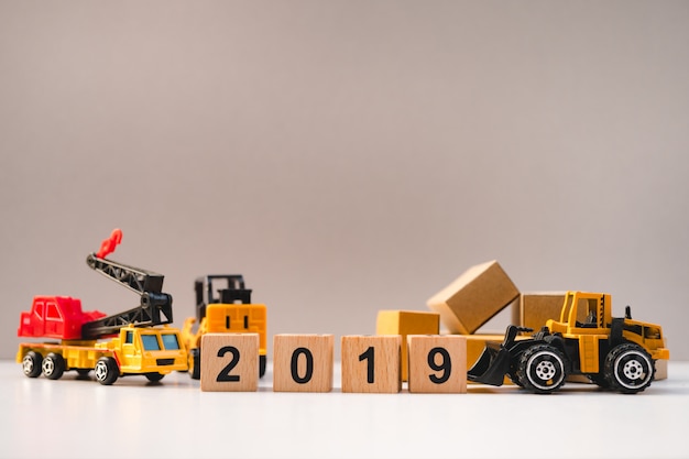 Holzblockjahr 2019 mit Baufahrzeug und Pappkartons als Logistikkonzept