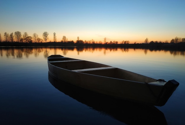 Holzboot auf einem großen schönen See bei Sonnenuntergang