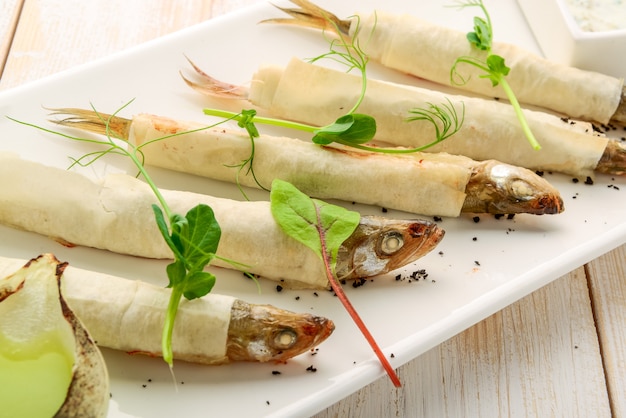 Holzbrett mit geschmolzenem gebratenem Fisch und Salat