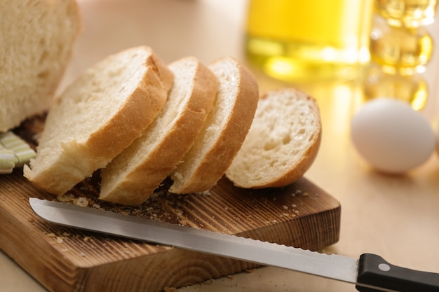 Holzbrett mit geschnittenem Brot und Messer auf Küchentisch