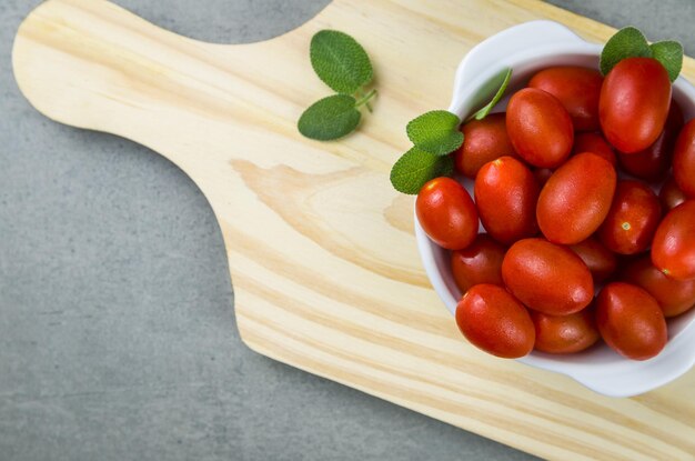 Holzbrett mit Kirschtomaten auf grauem Hintergrund. kulinarischer Hintergrund.