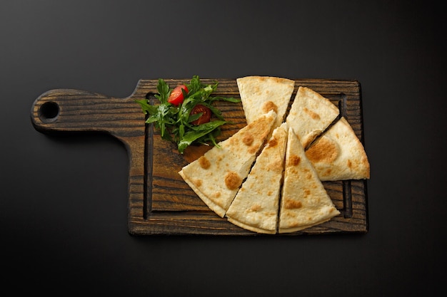 Holzbrett mit Lavash und Salat isoliert auf schwarzem Hintergrund