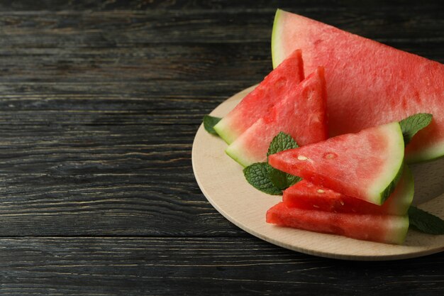 Holzbrett mit Wassermelonenscheiben und Minzblättern